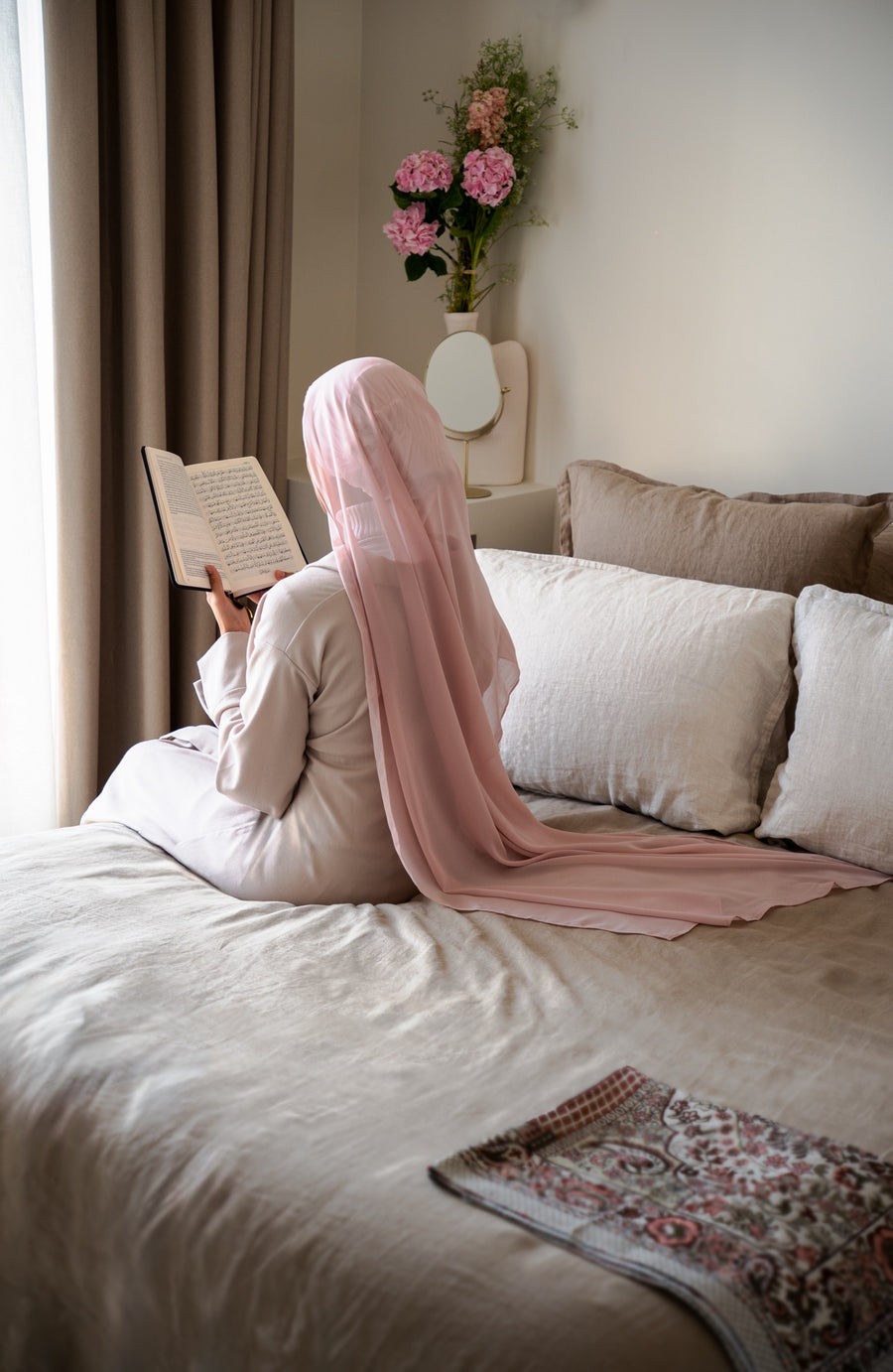 Hijabi lisant le Coran de dos, bonnet en soie de mûrier Una Hijabi visible sous un voile transparent