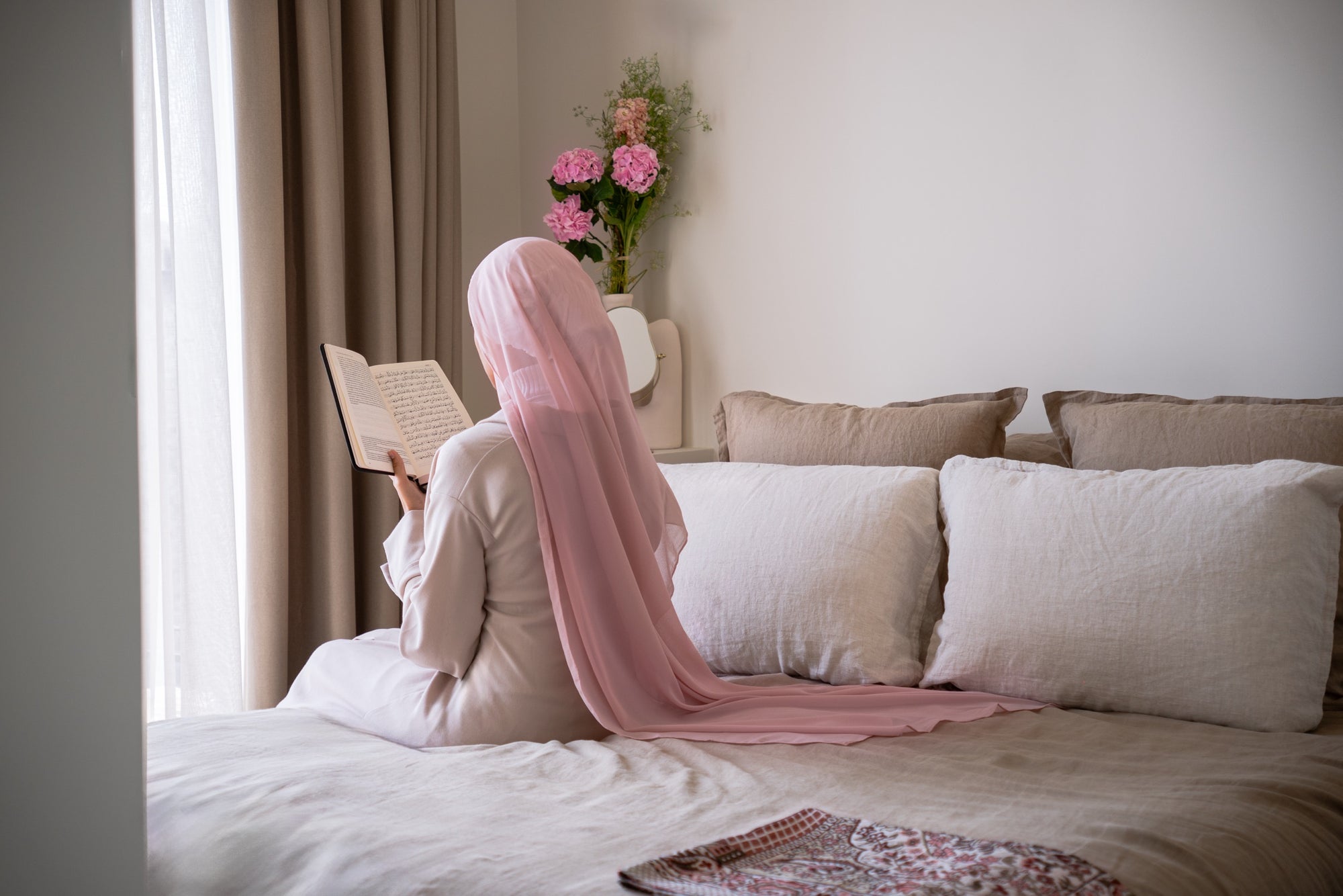 Hijabi lisant le Coran de dos, bonnet en soie de mûrier Una Hijabi visible sous un voile transparent