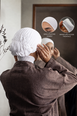 Bonnet Una Hijabi blanc en soie de mûrier porté devant un miroir, avec mention couture invisible et bande antiglisse frontale